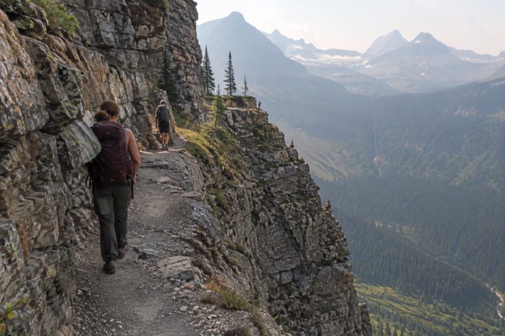 A narrow mountain road hugging a cliff face with a valley far below