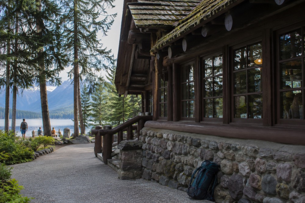 A historic lodge building beside a long mountain lake surrounded by forest