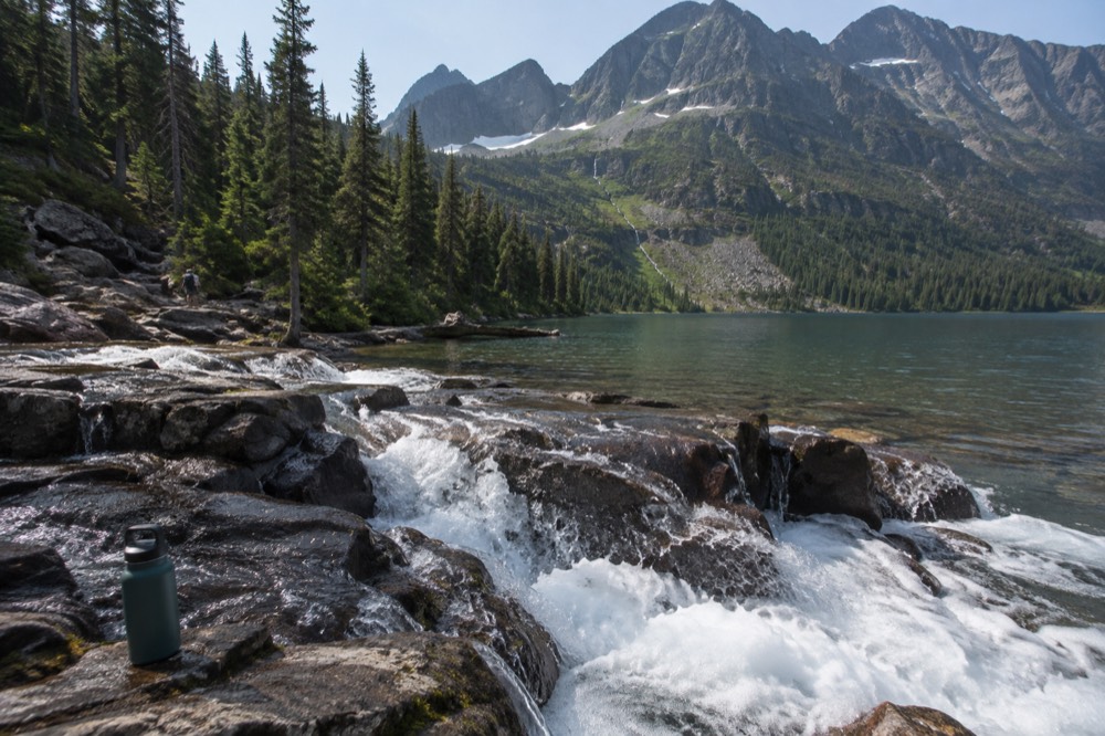 A river flowing through a forested valley with whitewater rapids and distant peaks