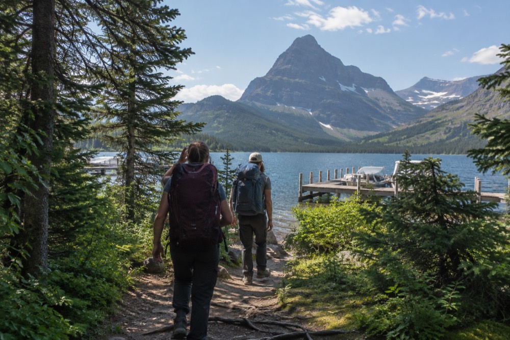 Passengers walking a short forest path between two lake docks on a clear morning