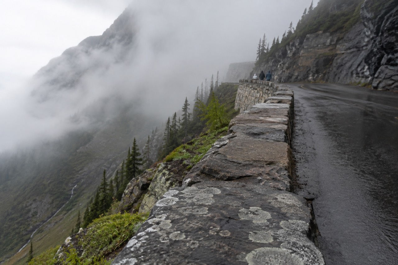 Going-to-the-Sun Road curving along a cliff face below tall mountains