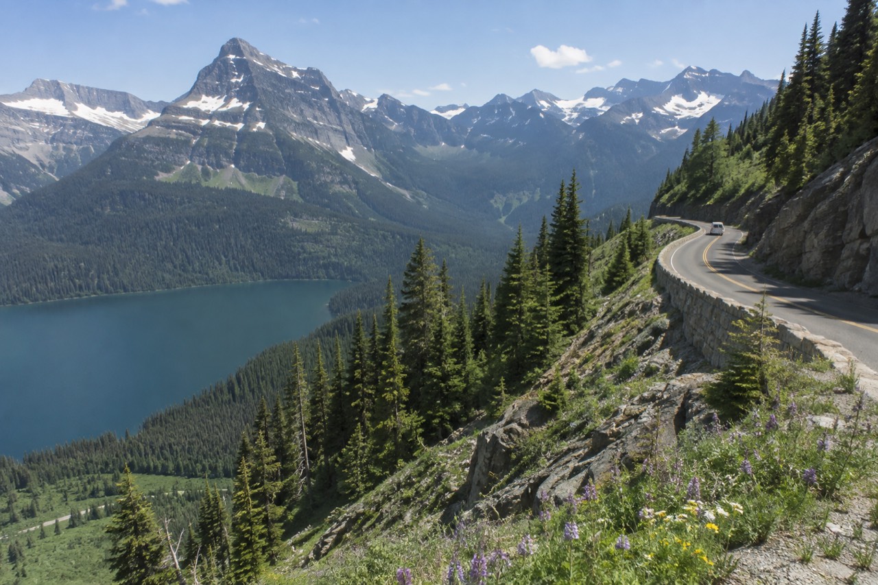 Going-to-the-Sun Road curving along a green mountainside above a glacial lake