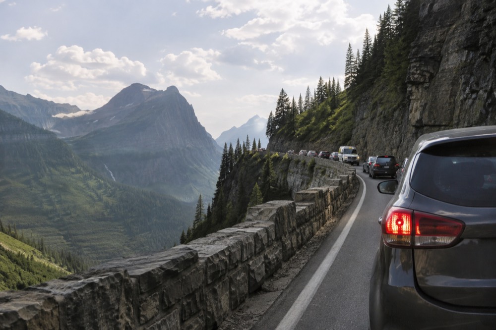 Traffic lined up along Going-to-the-Sun Road with cliffs above the pavement