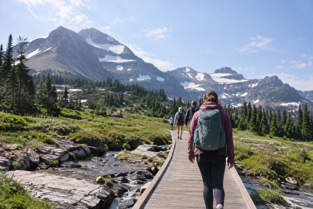 Visitors walking a boardwalk path near a visitor center beneath high peaks