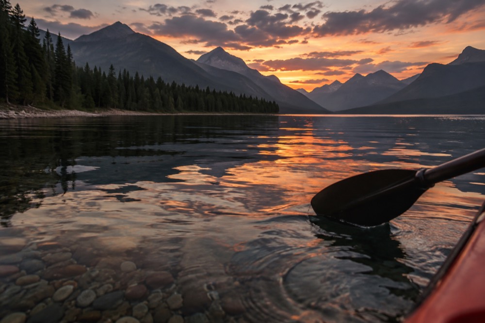 A calm lake at sunset with mountains reflected in still water
