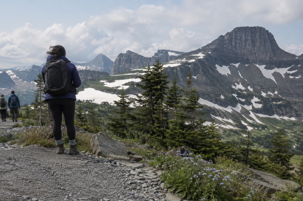 A mountain pass parking area with alpine meadows and a long ridgeline above
