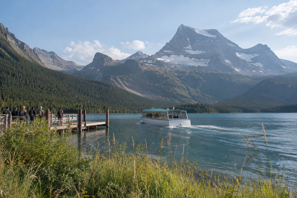 An alpine valley with a turquoise lake below a jagged glaciated peak