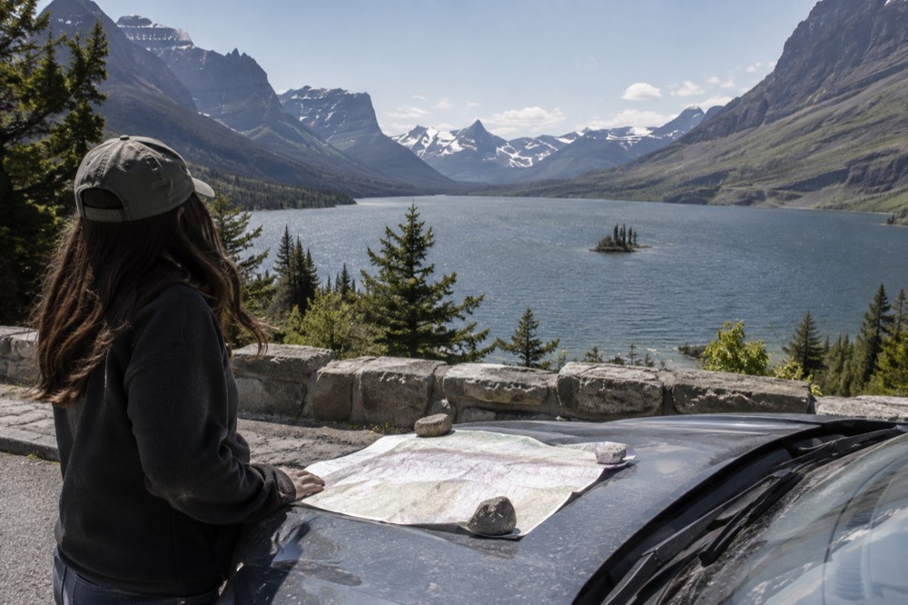 A rental car parked at a scenic overlook with a long mountain lake below