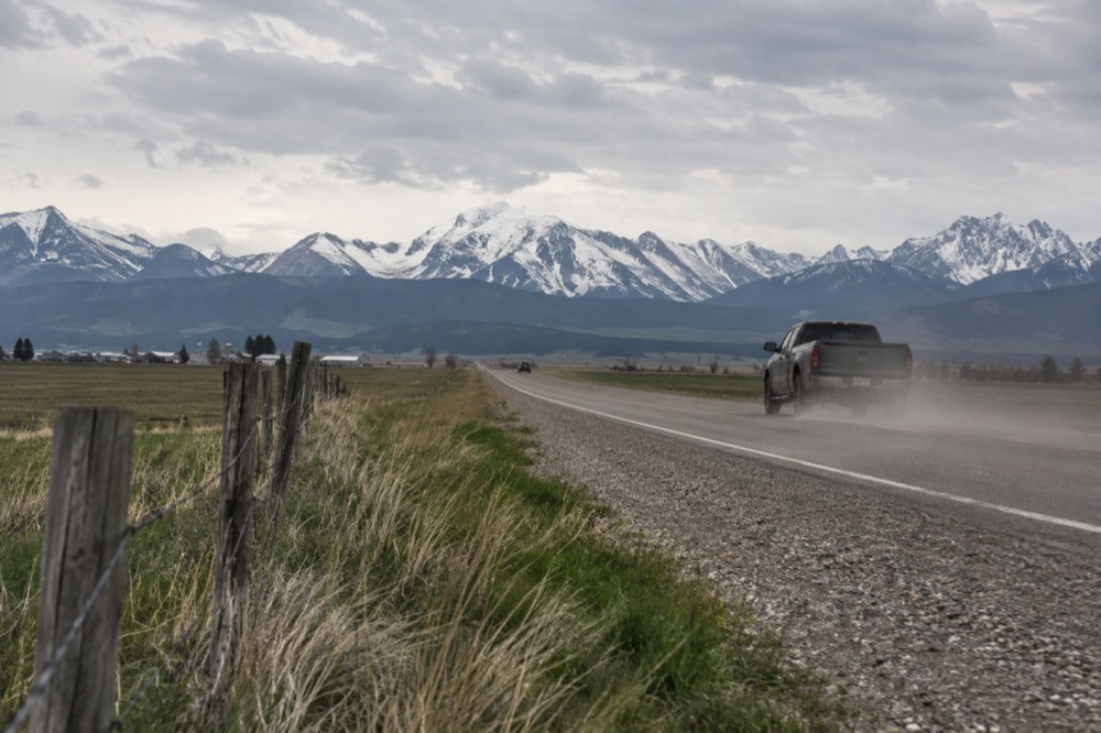 Highway stretching toward distant snowcapped mountains with a river running alongside