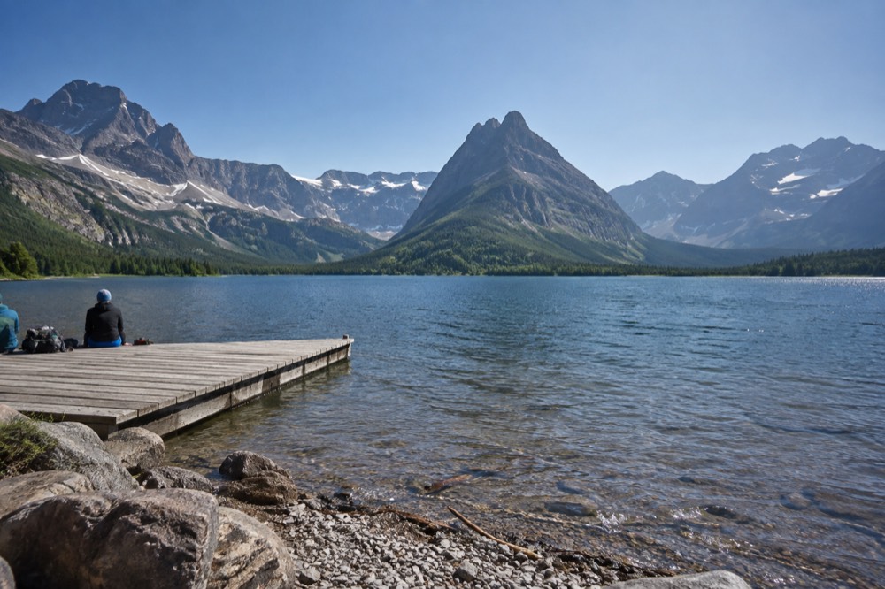 A wide alpine lake enclosed by steep rocky mountains under a clear sky