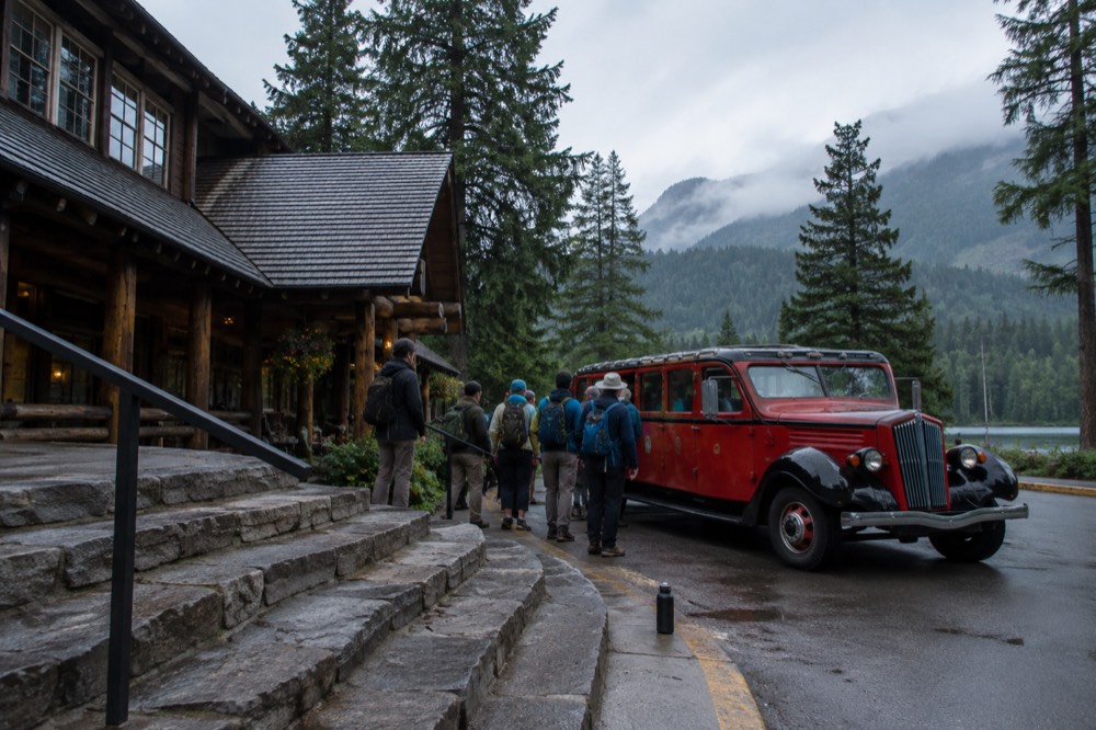 A group of passengers boarding a tour vehicle at a mountain lodge entrance