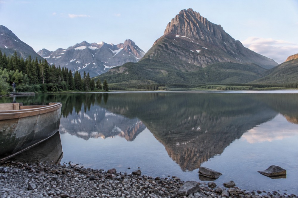 A calm mountain lake reflecting tall peaks in early morning light