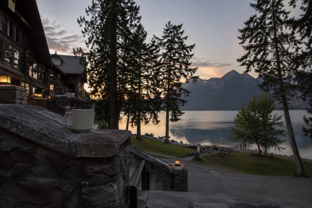 A long mountain lake surrounded by forest with a historic lodge on its shore