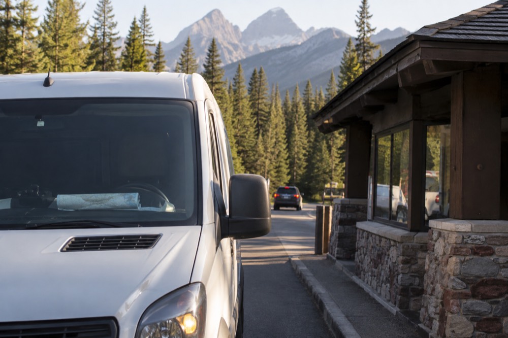 A vehicle stopped at a forested park entrance station in northwest Montana