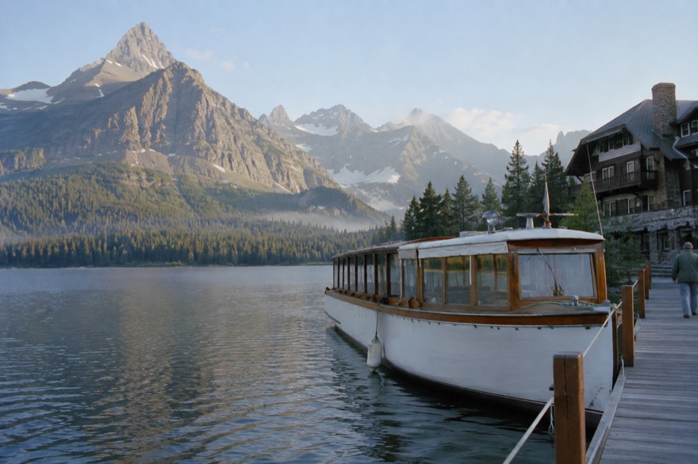A historic wooden boat docked on an alpine lake near a grand old hotel
