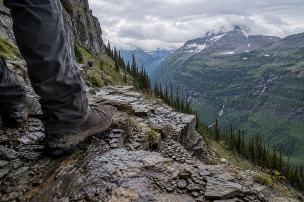 A hiker's boots on a rocky trail with a valley view