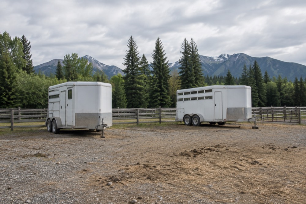 Empty horse trailers parked at a gravel trailhead under a wide sky