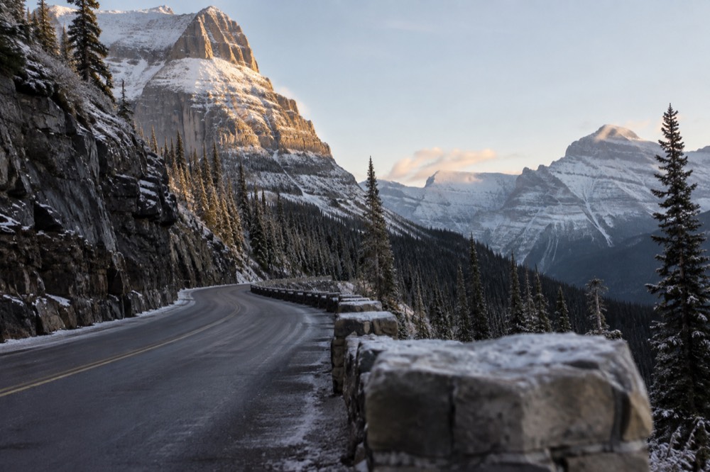 Snow covered peaks above a winding mountain road in early morning light