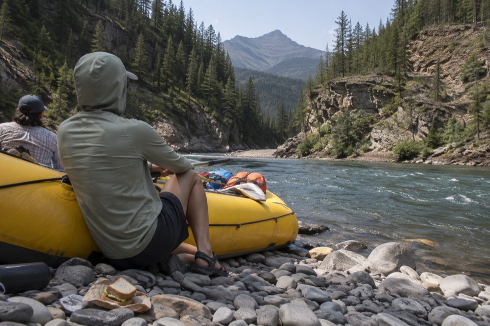 Rafters resting with a raft on a rocky riverbank at midday