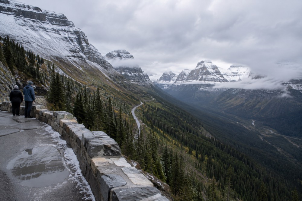 Fresh snow dusting high mountain peaks above a winding valley road
