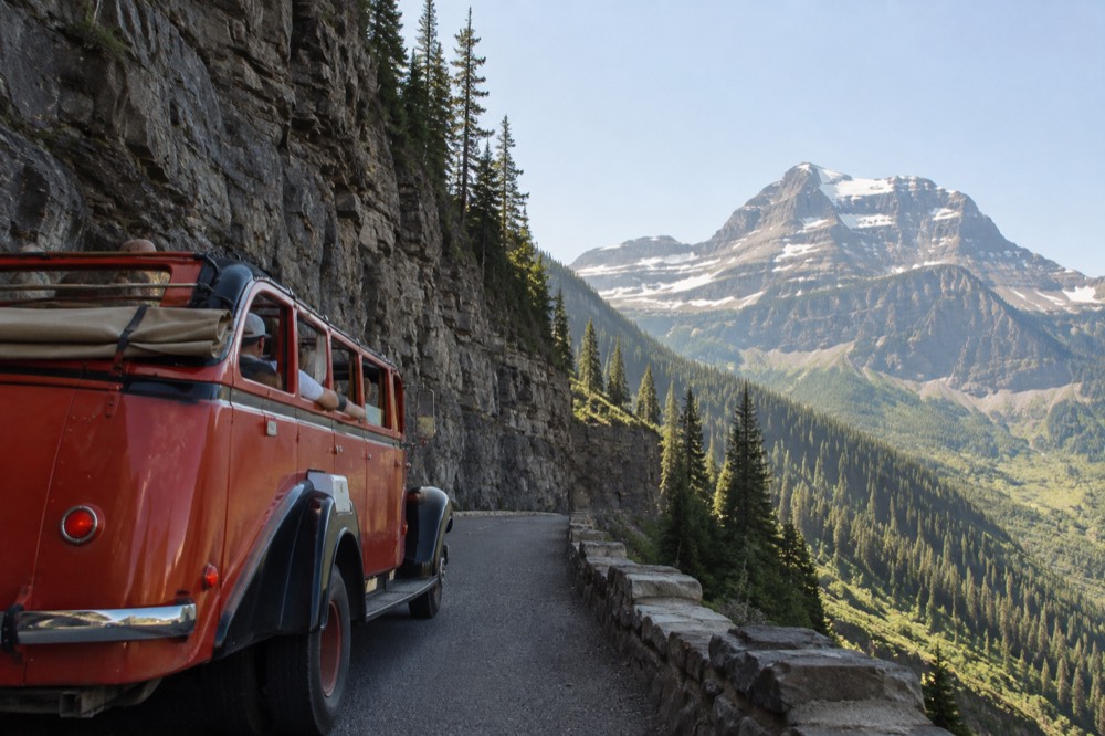 A historic red bus with roll-back top parked on Going-to-the-Sun Road