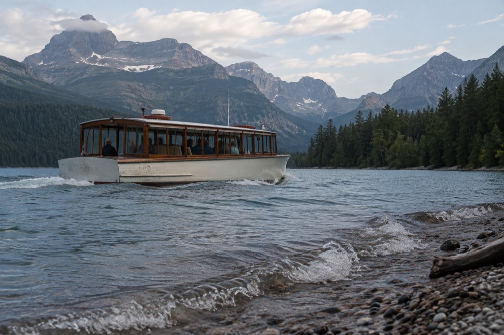 A historic wooden tour boat on Lake McDonald with mountains behind