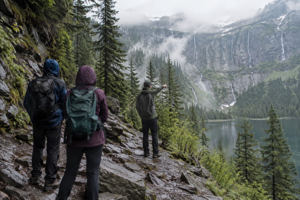 Small group hiking a rocky trail with a guide pointing out a feature