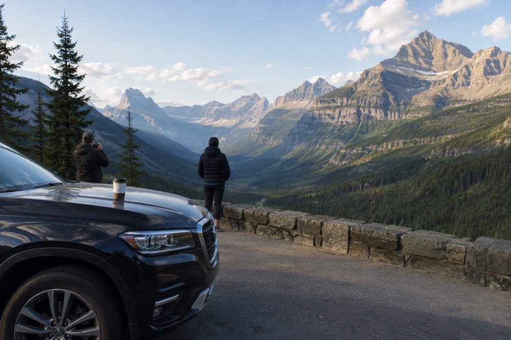 Luxury SUV parked at a scenic overlook with mountains in the background