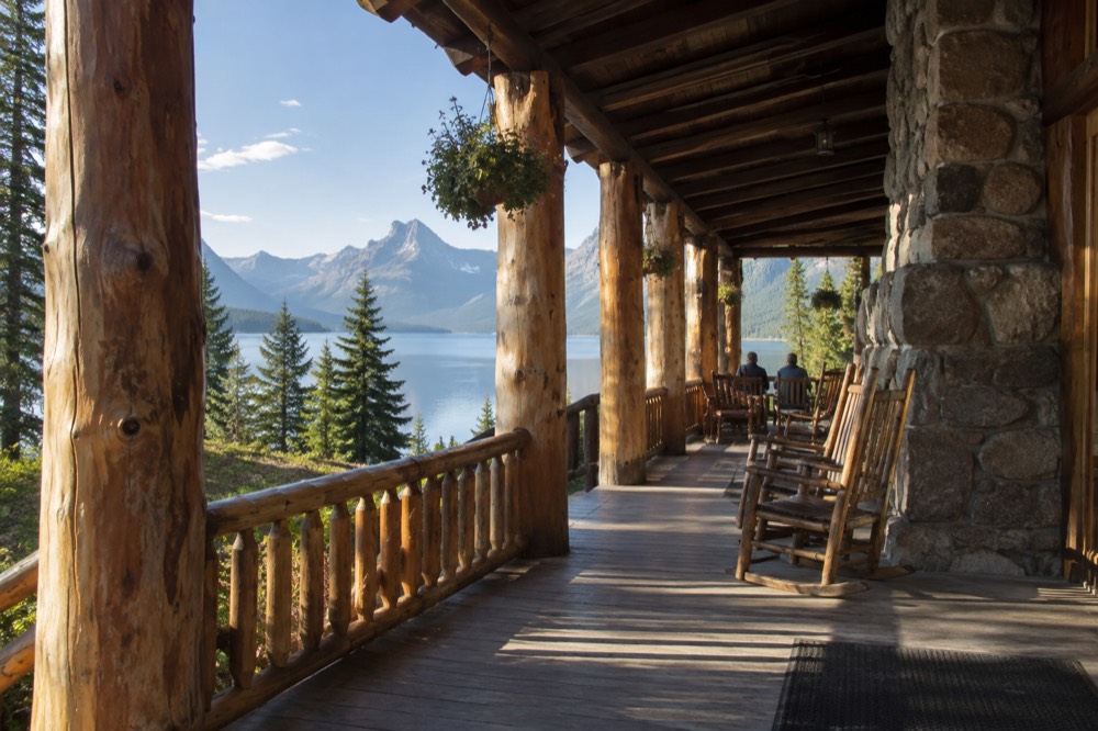 A log lodge building beside a lake with mountains behind it