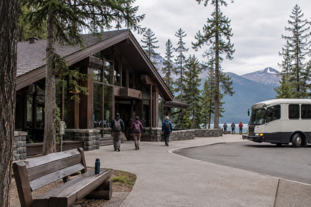 A shuttle bus parked at a visitor center with forested mountains behind