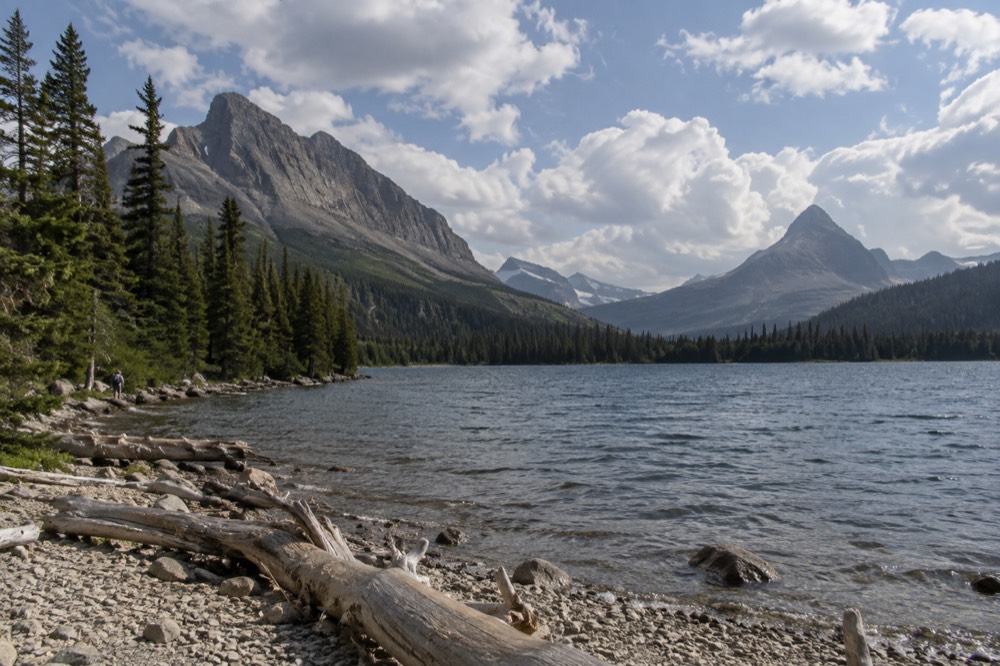 A mountain lake surrounded by evergreen forest under scattered clouds