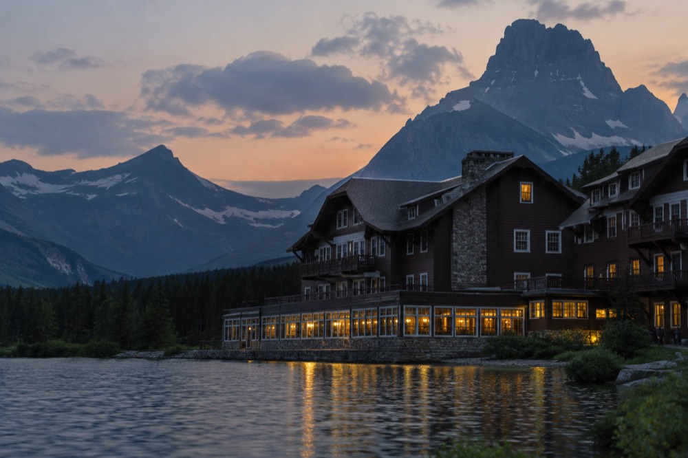 A historic wood-and-stone lodge beside a mountain lake at dusk