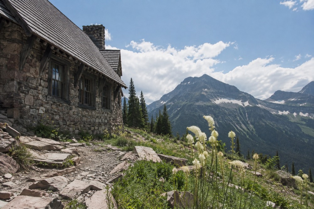A wooden chalet on a rocky alpine slope under a wide sky
