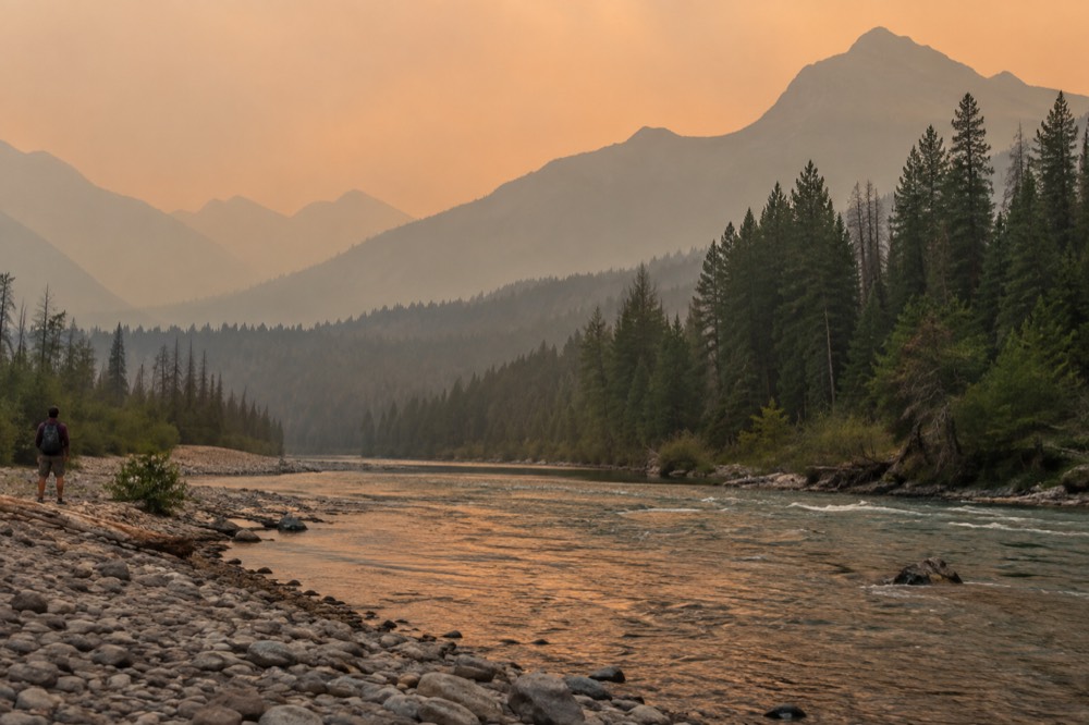 Hazy ridgelines under a smoky amber sky above a river valley