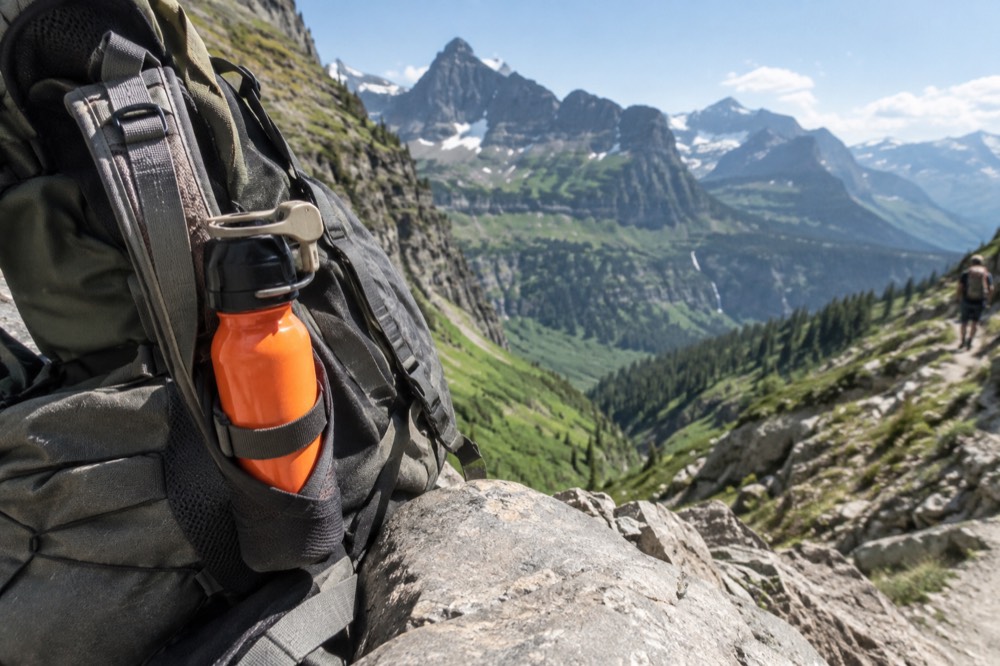 A bear spray canister clipped to the outside of a hiking pack