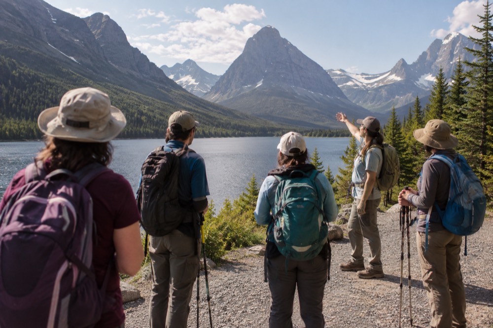 A small group with a guide pausing on a trail to look across a valley