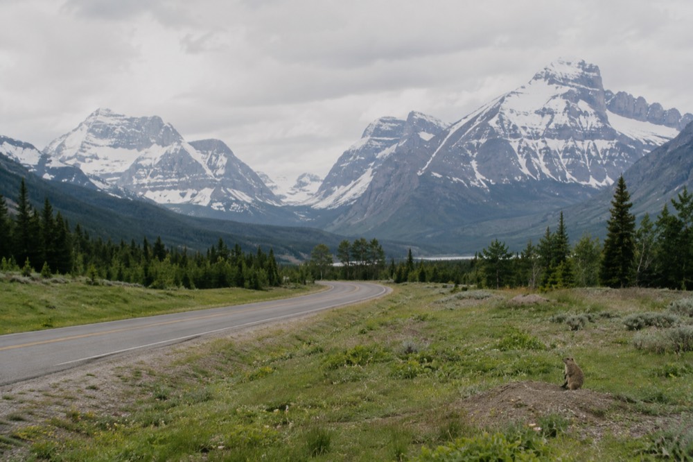 A valley road winding toward distant snowcapped peaks