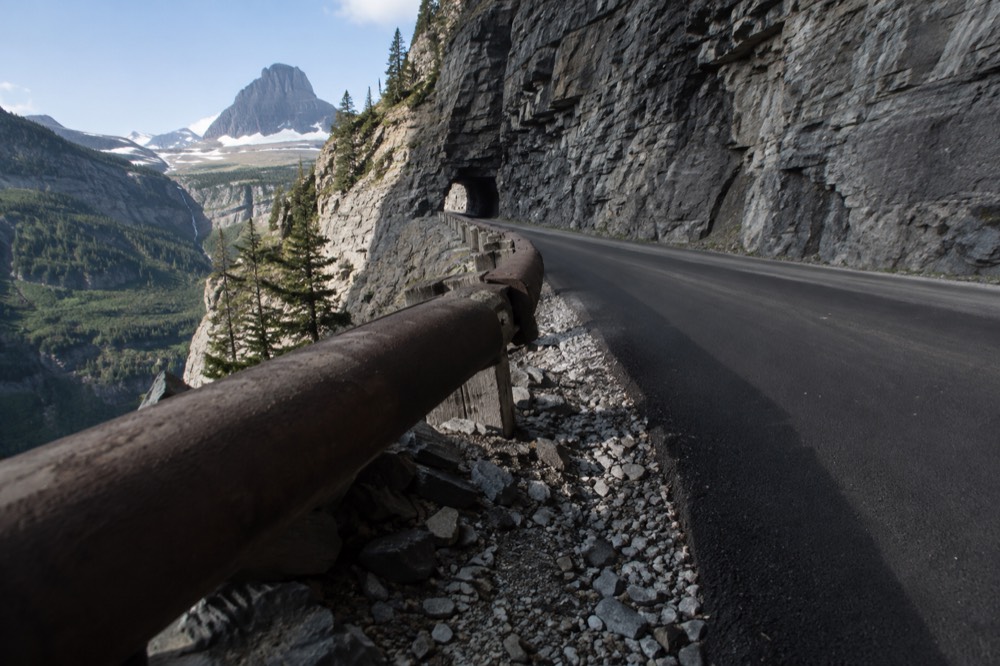 A narrow road cut into a rock cliff with a guardrail