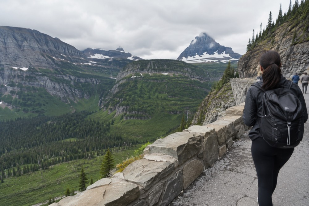A winding mountain road with stone guardrails above a forested valley
