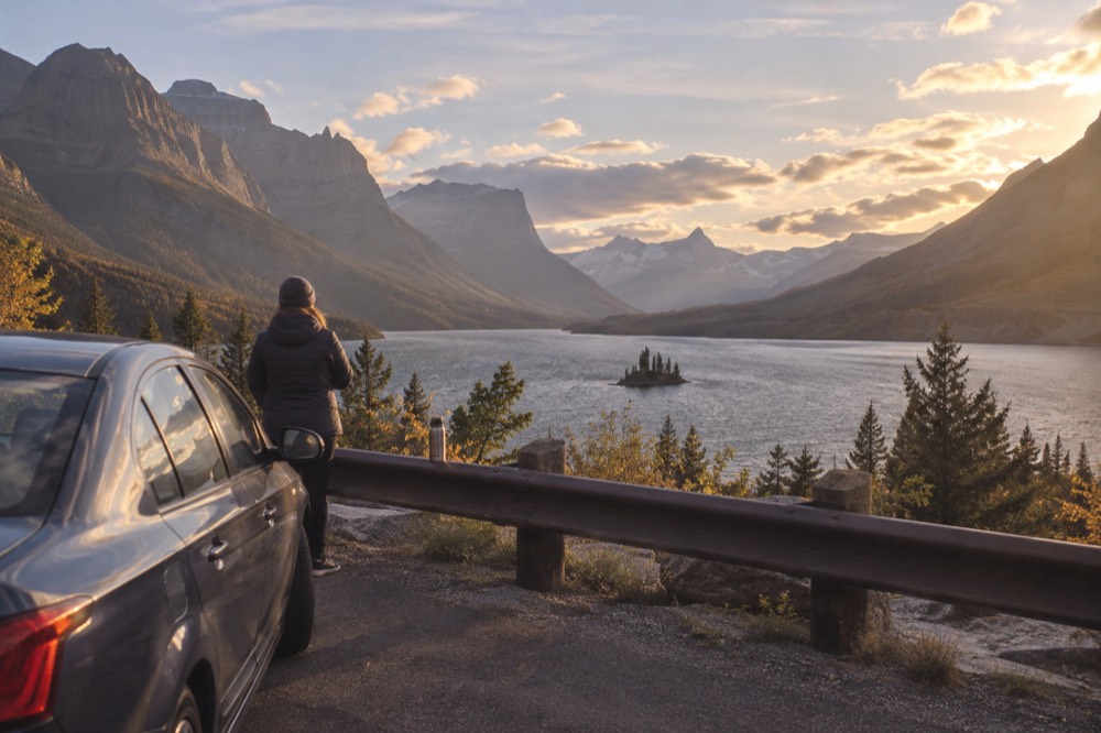 A car pulled over at a scenic turnout with a long view down a glacial valley