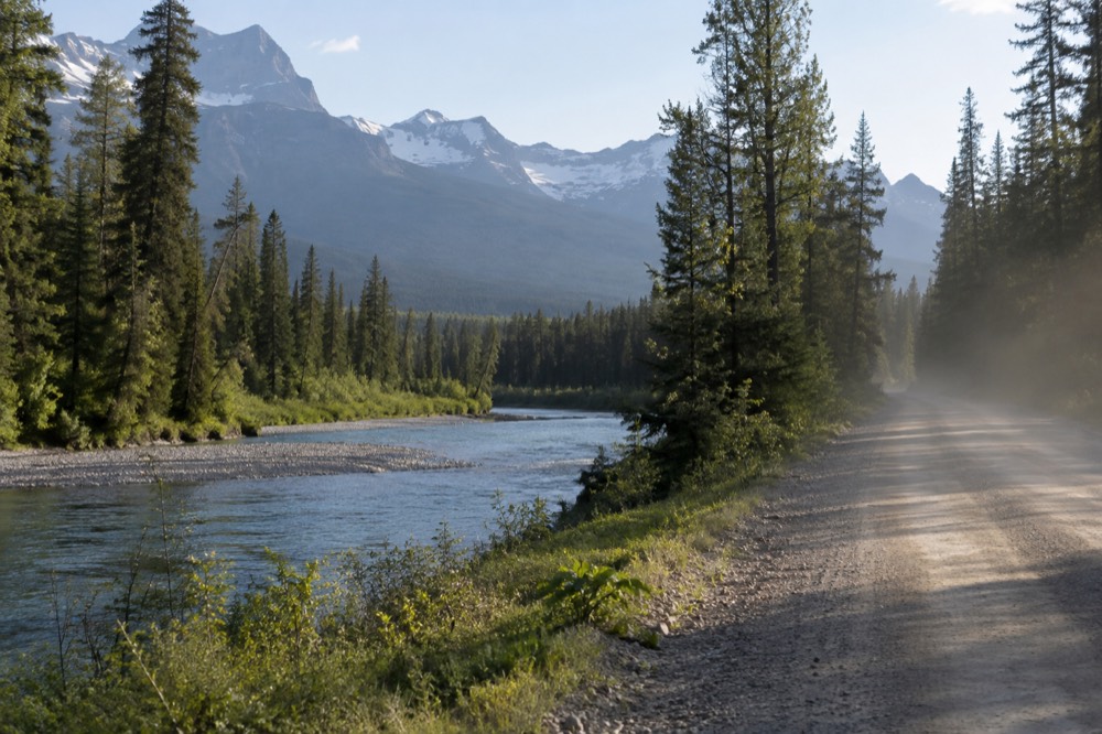 A calm river winding through a forested valley with mountains behind