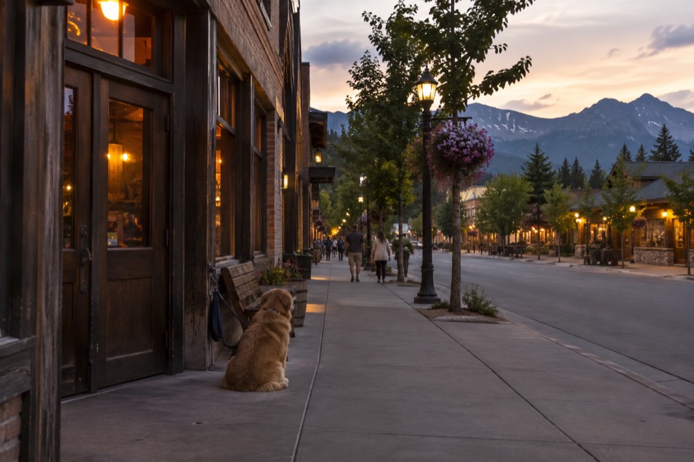 A small mountain town street at dusk with distant peaks