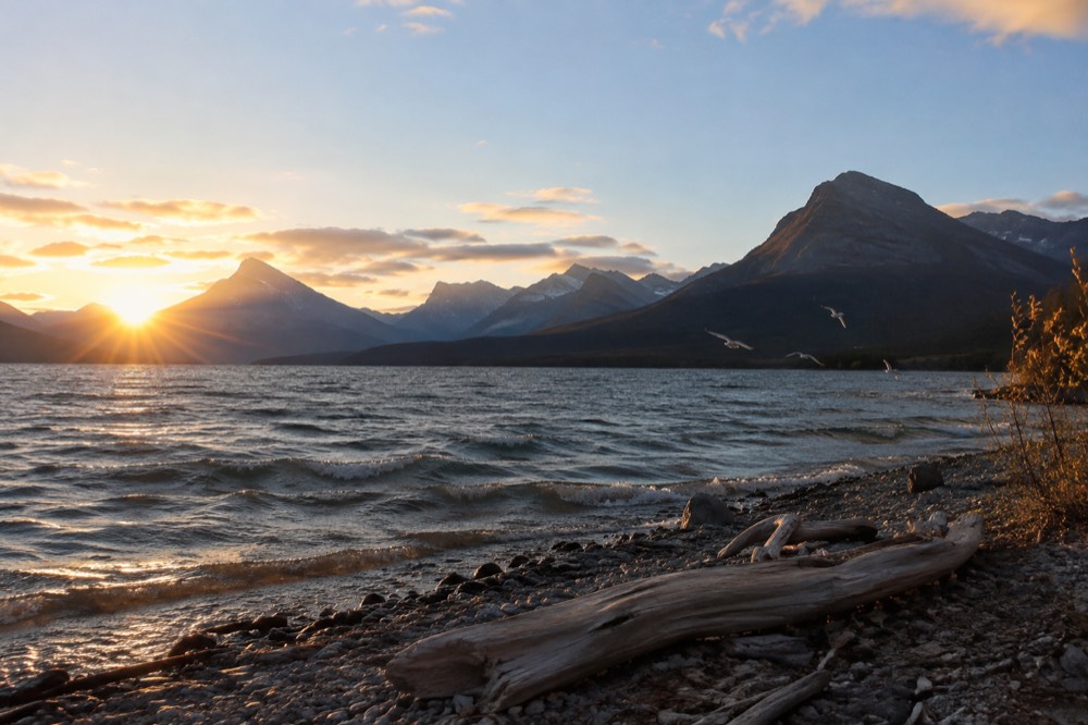 Sunrise over St. Mary Lake with mountains reflecting in the water.