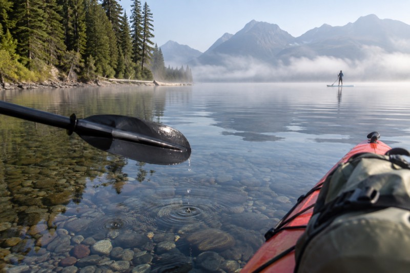 Clear kayaks lit by LED lights at sunset on a lake near Whitefish, Montana on a guided evening paddle tour